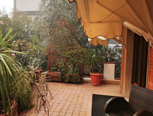 Vista del patio lussureggiante del Villa Alba Boutique Hotel con vegetazione rigogliosa, pavimentazione piastrellata e un'invitante area salotto.