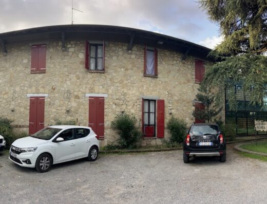 Villa e Roma: Facciata in pietra con finestre rosse, auto parcheggiate, architettura rurale e design moderno si incontrano.