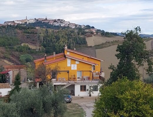 Villa Ferranti con vista panoramica su un borgo collinare, immersa nel paesaggio rurale italiano. Casa vacanze ideale per motociclisti.