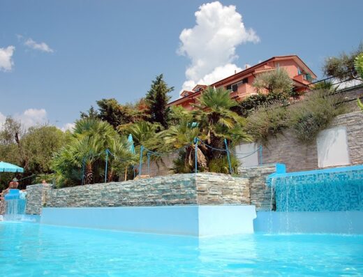 Piscina panoramica con cascata e vegetazione lussureggiante al Villa Giada Space Resort, ideale per vacanze e relax.