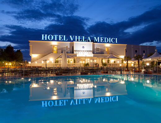 Villa Medici Hotel, Ricevimenti & SPA at dusk with lit facade reflecting in the pool, offering luxury accommodations and event services