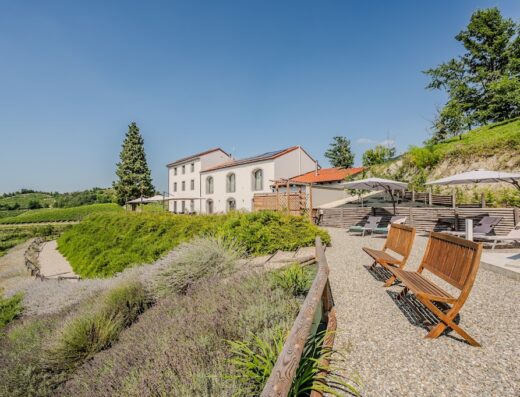 Villa Rocco Country House, Italia: vista esterna della villa con giardino fiorito, panchine in legno e ombrelloni per il relax.