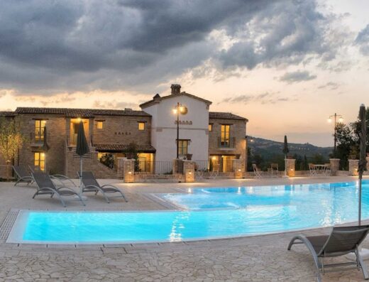 Villa Sant'Angelo at sunset, featuring a luxurious swimming pool and stone architecture under a dramatic sky, a travel destination.
