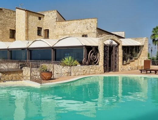 Villa Vittoria Hotel: vista esterna della piscina turchese con lettini, edificio in pietra con vetrate e dettagli in ferro battuto.