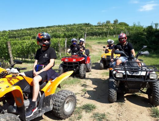 Escursione in quad tra le colline: un gruppo di persone guida quad colorati attraverso un paesaggio collinare con vigneti. Esperienza di viaggio e avventura.