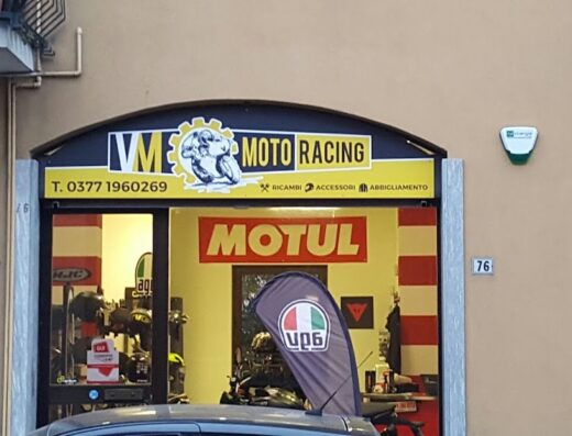 Negozio VM Moto Racing: ricambi, accessori e abbigliamento per moto. Insegna con logo, numero di telefono e vetrina con prodotti Motul, HJC e AGV.