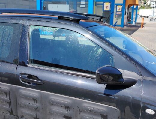 Auto sporca in un autolavaggio con gocce d'acqua sulla carrozzeria, servizio di pulizia veicoli, manutenzione auto