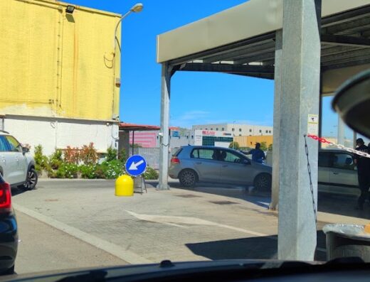 Autolavaggio Wash Service S.R.L: auto in fila per il lavaggio, operatore al lavoro, segnaletica stradale visibile.