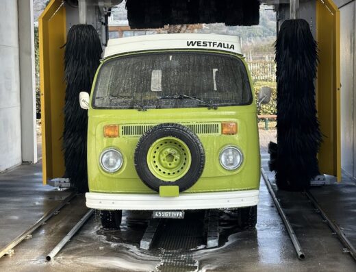 Un furgone Volkswagen Westfalia verde vintage entra in un autolavaggio Stargate S6 per un servizio di pulizia auto.