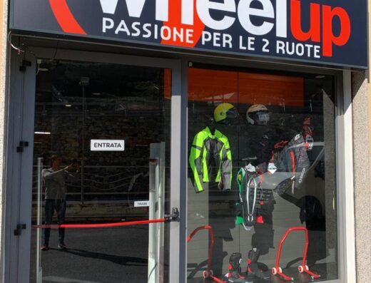 Ingresso del negozio Wheelup, specializzato in accessori e abbigliamento per moto. In vetrina caschi, giacche tecniche e stivali da motociclista.
