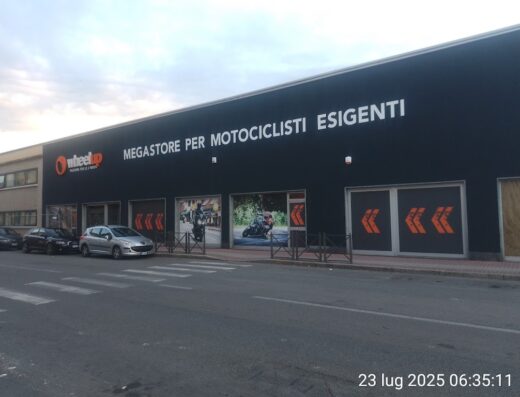 Immagine del negozio Wheelup, megastore per motociclisti esigenti, con auto parcheggiate di fronte. Accessori e abbigliamento moto disponibili.