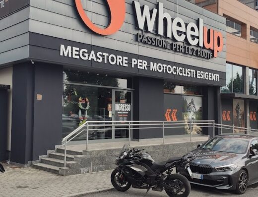 Wheelup megastore per motociclisti esigenti, negozio di accessori e abbigliamento moto. Moto parcheggiate di fronte all'ingresso. Passione per le 2 ruote.