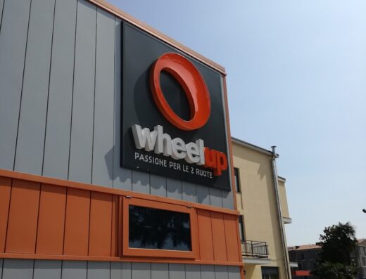 Insegna Wheelup con moto parcheggiata, negozio di accessori e servizi per motociclisti, passione per le due ruote.