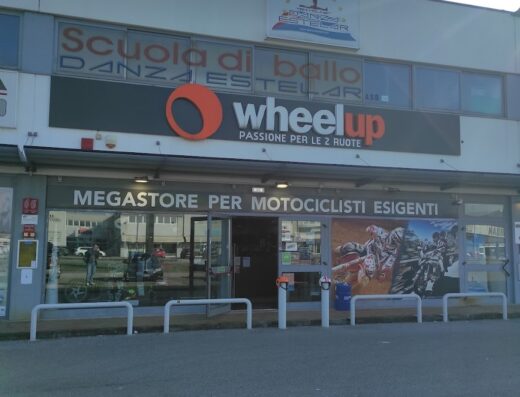 Wheelup megastore per motociclisti esigenti: negozio di accessori e abbigliamento moto. Vetrina con poster di motocross e passione per le due ruote.