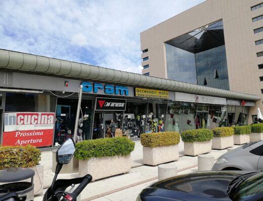 Facciata del negozio Wheelup (ex Oram) a Modena, specializzato in accessori moto e abbigliamento tecnico Dainese. Si nota l'insegna e vetrine con caschi e tute da moto.