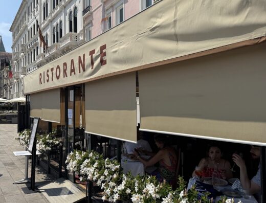 Ristorante in Italia con tavoli all'aperto e fioriere bianche, tipico locale per viaggiatori e appassionati di lifestyle e cultura italiana.