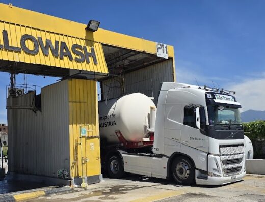 Un camion cisterna bianco della Silo Trans AC in fase di lavaggio presso Yellowash Centro Servizi Autoveicoli di Alcamo, con struttura gialla sovrastante.